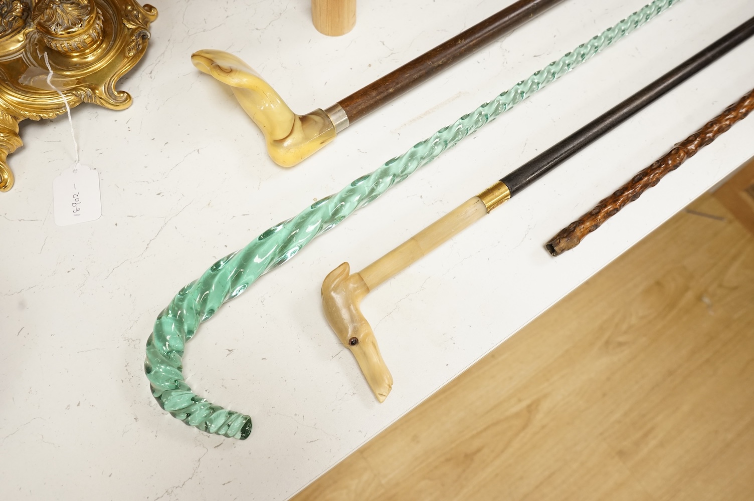 Four walking sticks to include a Brigg of London with carved horn handle in the form of a dogs head and a barley twist glass example, largest 123cm in length